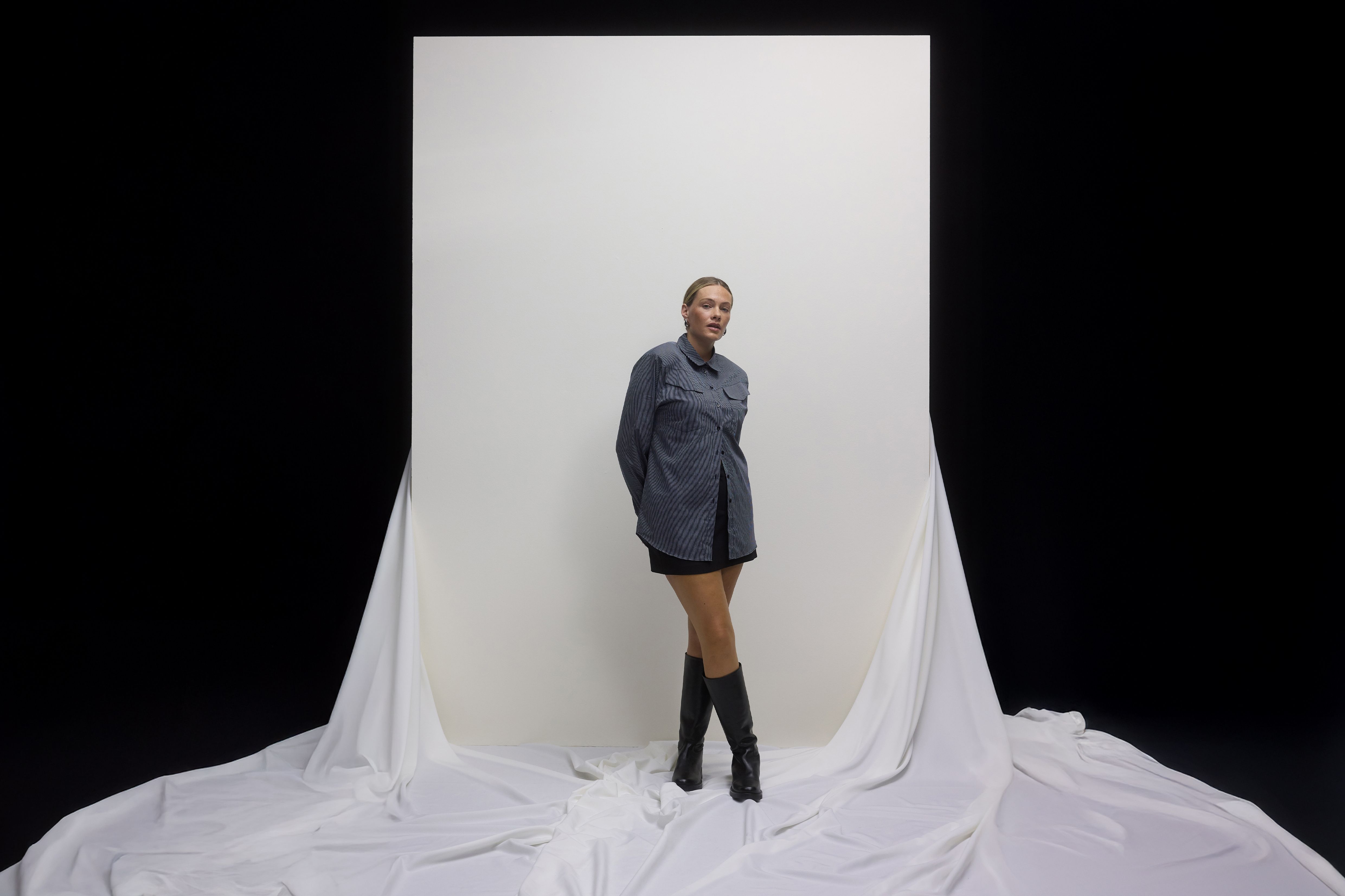 Femme portant une chemise à rayures, une mini-jupe et des bottes.