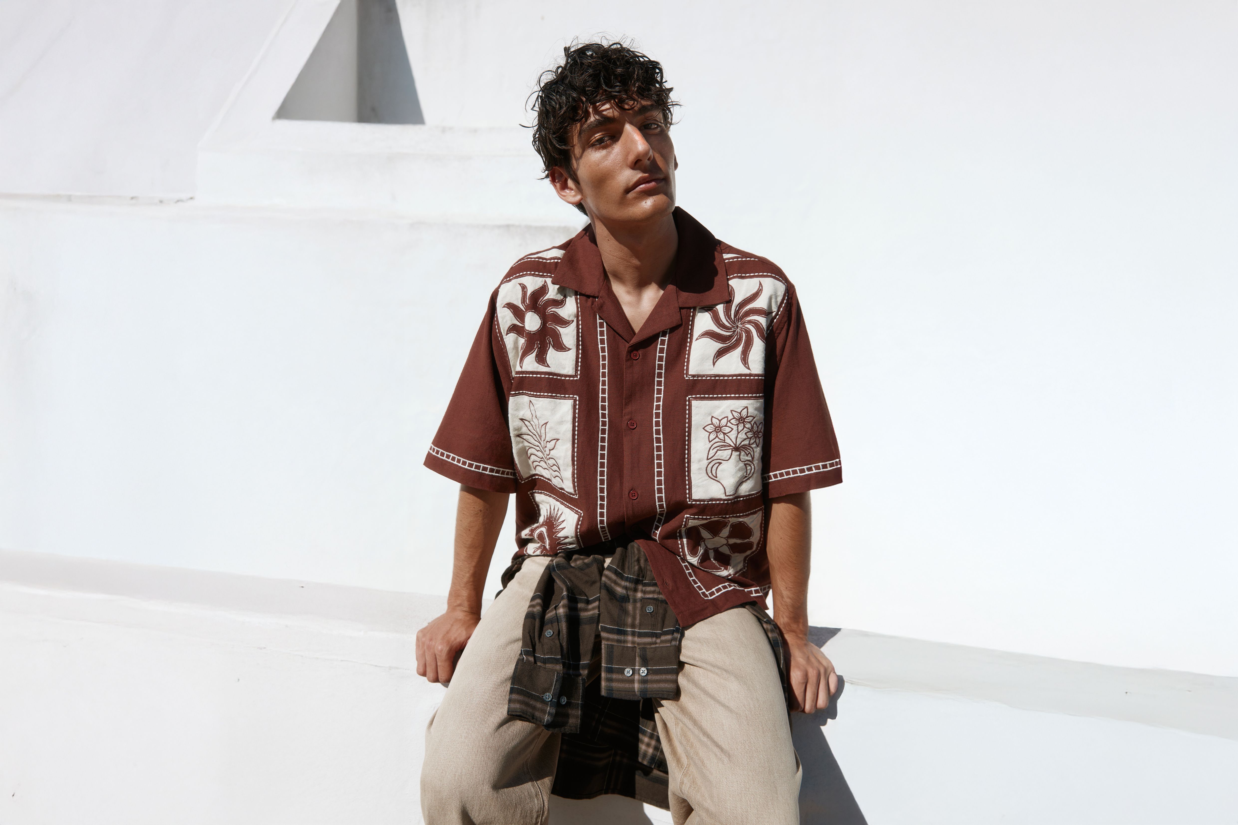 Homme assis portant une chemise marron à manches courtes